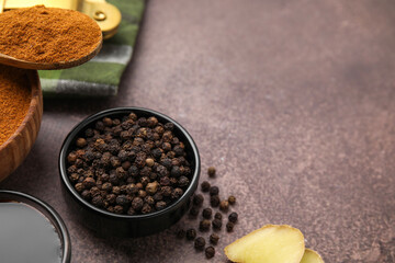Aromatic peppercorns and different fresh ingredients for marinade on brown table. Space for text