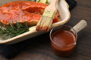 Fresh marinade, fish, rosemary, lime and brush on wooden table, closeup