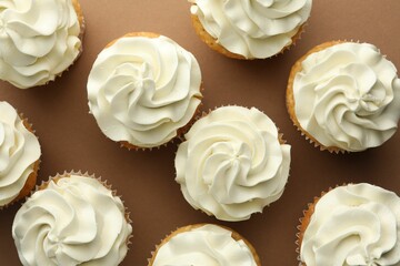 Tasty vanilla cupcakes with cream on dark beige background, top view