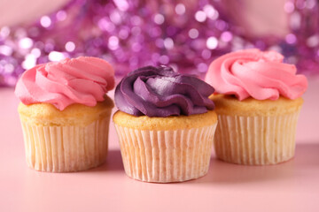 Delicious cupcakes with bright cream on pink background, closeup