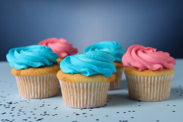 Delicious cupcakes with bright cream and confetti on blue background, closeup