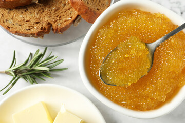 Fresh pike caviar in bowl, bread, rosemary and butter on white table, flat lay