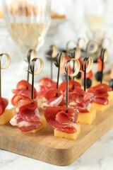 Different tasty canapes on white marble table, closeup