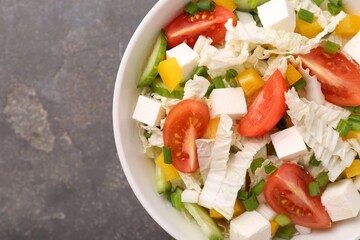 Tasty salad with Chinese cabbage, tomato, cheese, pepper and cucumber on grey table, top view