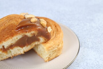 Tasty puff pastry. Supreme croissant with chocolate paste and nuts on grey table, closeup. Space...