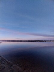 A panoramic view of the lake at dusk, with clear blue skies and gentle ripples on its surface. 