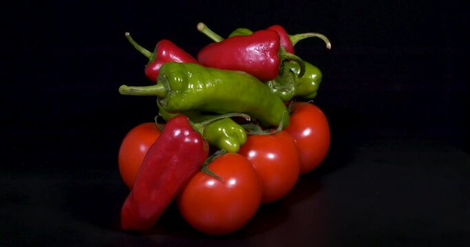 Close-up footage of tomatoes, red and green peppers on black background.