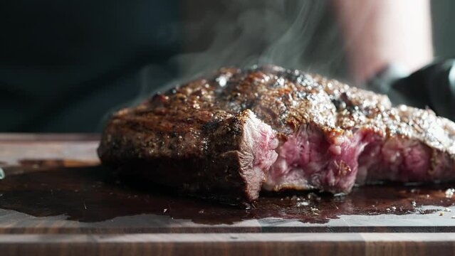  Meat lies on a purple cutting board and emits smoke , preparing food for a cookery event. The art of cooking involves skilfully cutting and slicing ingredients to create a delicious recipe