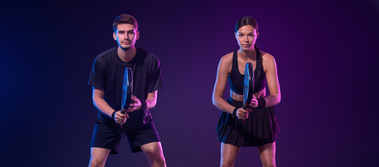 Padel tennis doubles. Two athletes players with racket. Man and woman with paddle racket on court....
