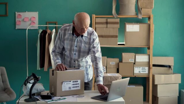 Older businessman entrepreneur, clothing seller using laptop checking e-commerce order packing in online shop