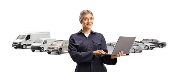 Female worker in a navy blue overall uniform with a laptop computer in front of vans