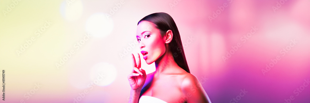 Wall mural young woman v sign - victory symbol in blur studio pink light