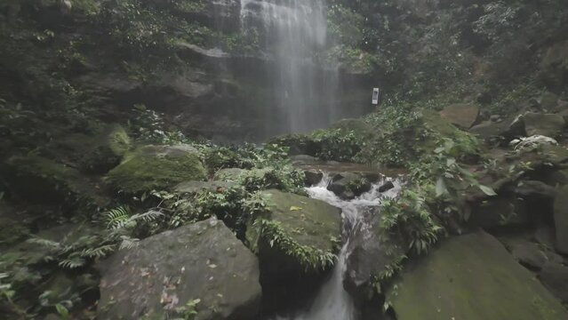 Drone flies along creek toward Cachoeira Escorrega Macaco as camera pans to top of waterfall