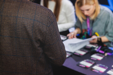 Process of checking in on a conference congress forum event, registration desk table, visitors and attendees receiving a name badge and entrance wristband bracelet and register electronic ticket