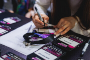 Process of checking in on a conference congress forum event, registration desk table, visitors and attendees receiving a name badge and entrance wristband bracelet and register electronic ticket