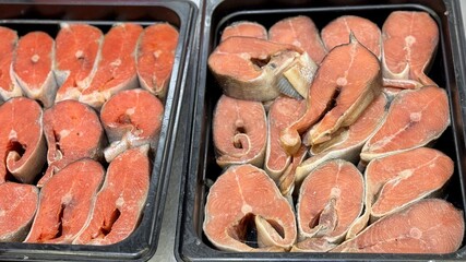 Sockeye salmon and chum salmon steaks from frozen raw materials on a substrate on a showcase for sale in a supermarket. Close-up