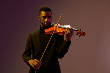 Elegant musician in black suit playing violin against purple background, creating beautiful music...