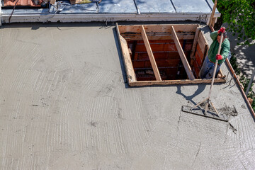 Construction worker leveling concrete on a roof slab.