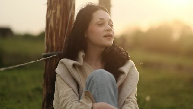 Portrait of calm young woman looking ahead and exhaling fresh air taking deep breath and reducing stress after hard dat at countryside Serene dark haired female resting for peaceful mind outdoors