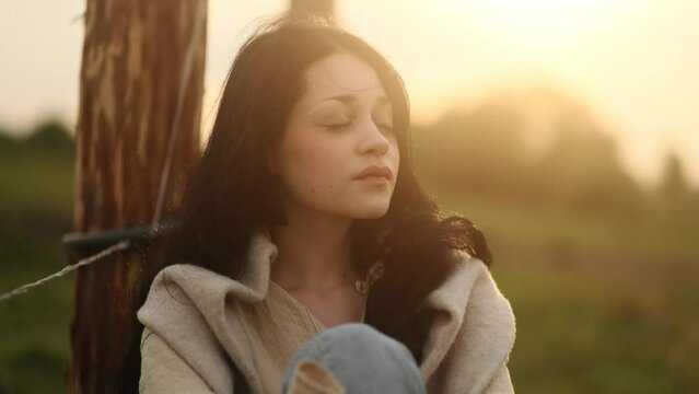 Portrait of calm young woman looking ahead and exhaling fresh air taking deep breath and reducing stress after hard dat at countryside Serene dark haired female resting for peaceful mind outdoors