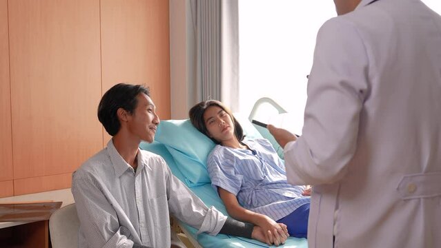Asian medical obstetrician doctor diagnosis examines reports using tablet for threatened miscarriage symptoms to patient woman while husband holding hands and accepts treatment procedure recovery
