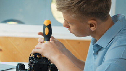 Close up of young student tighten the nut by using screwdriver. Caucasian teenager repairing or...