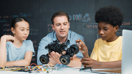 Smart teacher inspect car model construction to diverse student. Highschool children with mixed...