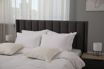 Many soft white pillows and duvet on bed indoors