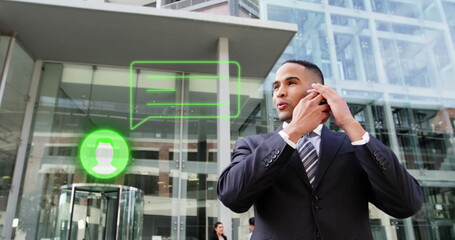 A young biracial man in suit talking on a smartphone outside office building