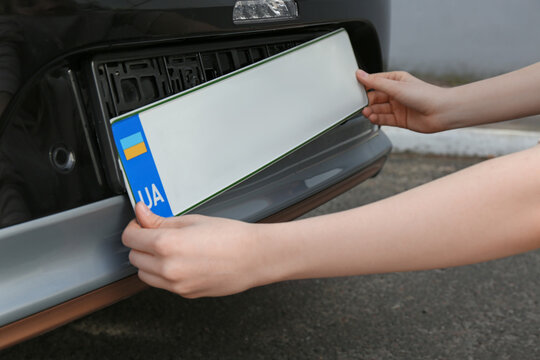 Woman installing vehicle registration plate outdoors, closeup
