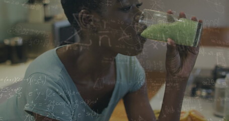 African American professional colleague drinking green juice, equations overlay