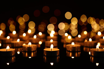 Burning candles on mirror surface in darkness, bokeh effect