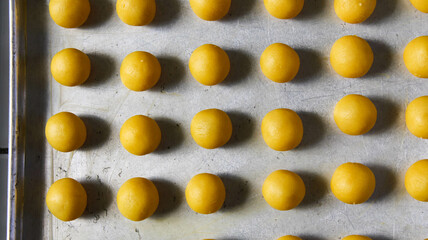 Nastar cakes are arranged in a row on a baking sheet and ready to be baked. ready-to-bake nastar cakes