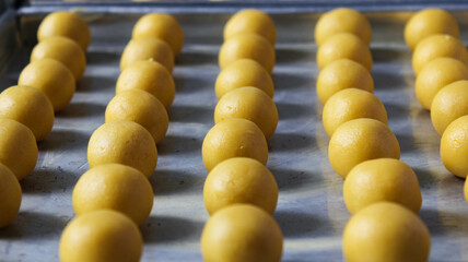 Nastar cakes are arranged in a row on a baking sheet and ready to be baked. ready-to-bake nastar...