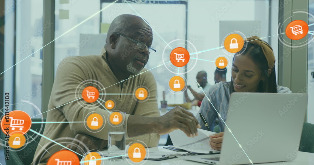 Poster Image of connected icons over diverse coworkers discussing reports on laptop in office