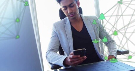 Image of connected icons globes over biracial man scrolling on smartphone at office