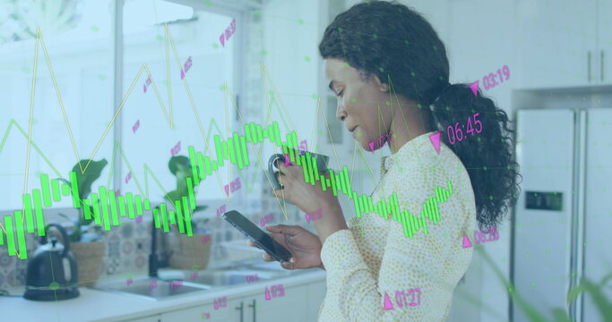 Image of graphs with changing numbers, biracial woman scrolling on cellphone while drinking tea - Powered by Adobe