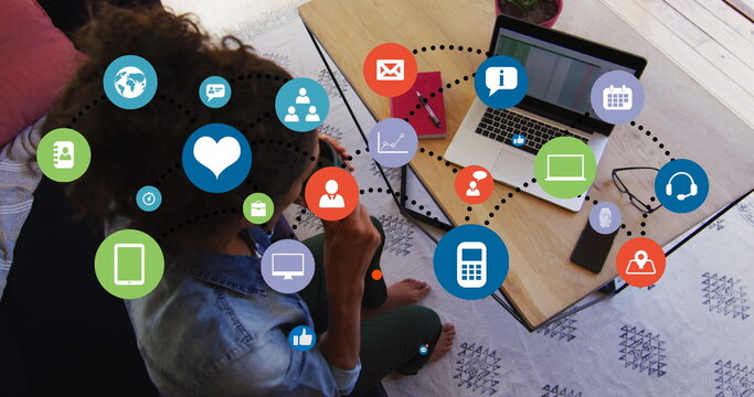 Image of network of digital icons over biracial woman drinking documents and using laptop