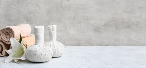 Spa composition with towels, lily flower and herbal bags on grey background with space for text