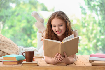 Young woman reading book near window