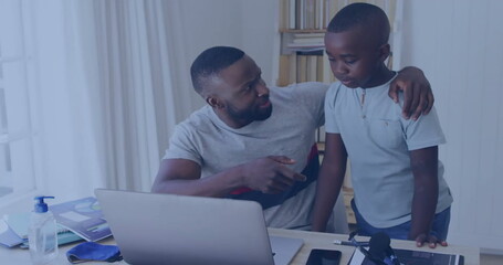 African American father pointing at laptop screen, son watching closely