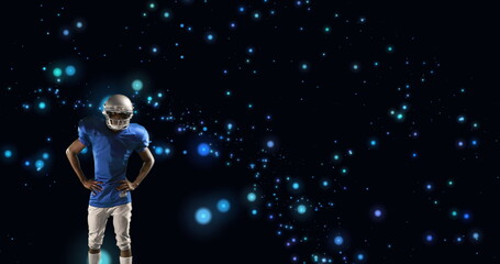 Image of american football player in helmet with arms crossed over glowing blue spots