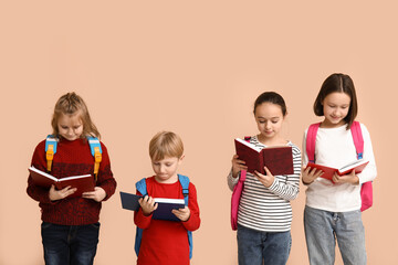 Little schoolchildren reading  books on beige background