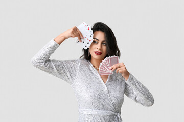 Beautiful young African-American woman with playing cards on white background