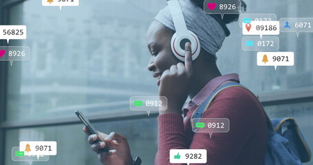 Image of social media icons with numbers over african american woman using smartphone