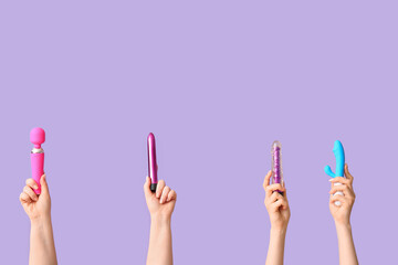 Female hands with vibrators on lilac background