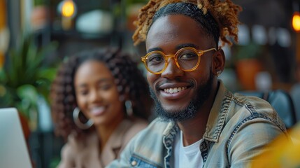 Smiling young man with dreadlocks sitting in a cafe with a friend.