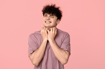 Young man with allergy scratching himself on pink background