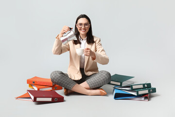 Businesswoman with coffee and many folders on light background