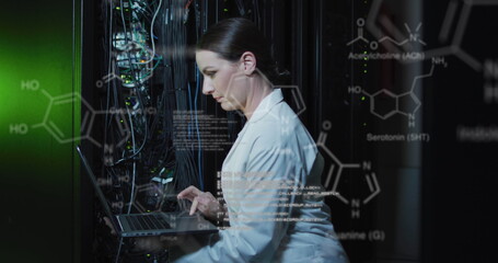 A caucasian female it technician is using a laptop to check a computer server